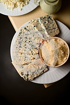 Cheese with mold and chopped parmesan. Different types of cheese on white plate, top view.