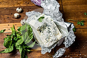 Cheese with a mold and a grass on a wooden background