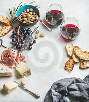 Cheese, olives, grapes, prosciutto, baguette and red wine, copy space