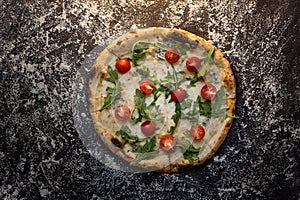Cheese pizza with flour on dark concrete background top view