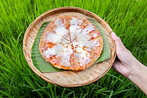Cheese pizza on traditional bamboo weave plates and banana leaf on hand with jasmine rice