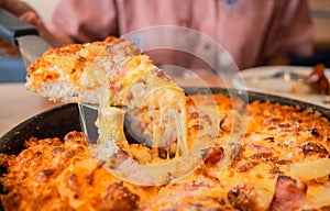 Cheese pizza on wooden board. slid piece growing cheddar cheese, restaurant table. fastfood concept