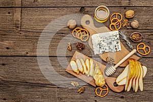 Cheese plate antipasti with smoked and blue cheese, crackers, honey, walnuts and ripe pear. Traditional snack recipe idea. Wooden