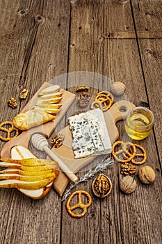 Cheese plate antipasti with smoked and blue cheese, crackers, honey, walnuts and ripe pear. Traditional snack recipe idea. Wooden
