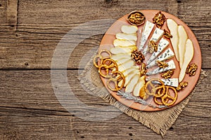 Cheese plate antipasti with smoked and blue cheese, crackers, honey, walnuts and ripe pear. Traditional snack recipe idea. Wooden