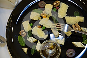 Cheese plate. Assortment of cheese with walnuts, bread an honey on stone slate plate