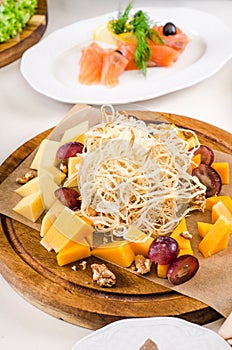 Cheese plate Assortment of various types of cheese on olive wood plate. Served for holiday banquet restaurant table with dishes,