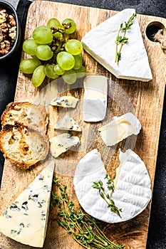 Cheese plate with Camembert, brie and blue cheese with grapes and walnuts. Black background. Top view