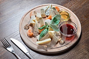 Cheese plate with cheeses Dorblu, Parmesan, Brie, Camembert and Roquefort in serving on the table from an old tree.