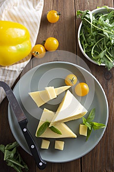 Cheese plate with delicous cheese slices and a cheese knife, wooden table. Top view