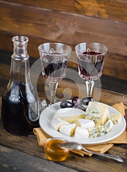 Cheese plate with grape and wine on wood