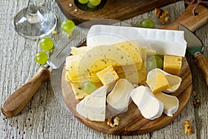 Cheese plate with grapes,  wine glass and nuts.