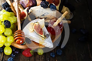 Cheese plate served with wine, jam and stick with honey