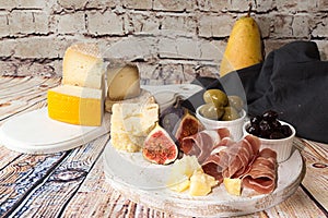 Cheese plate with Slices and blocks of cheese, prosciutto, olive