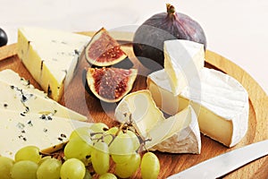 Cheese plate - various types of cheeses and figs and grapes on a
