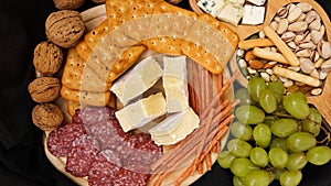 Cheese platter with assorted cheeses, grapes, nuts over black background