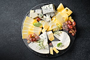 Cheese platter with craft cheese assortment at black background.