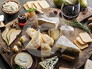 Cheese platter with different cheeses, fruits, nuts and wine on stone background. Top view. Tasty cheese starter