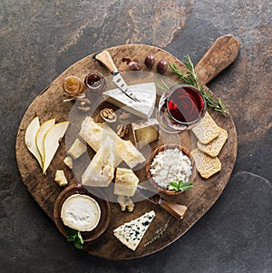 Cheese platter with different cheeses, fruits, nuts and wine on stone background. Top view. Tasty cheese starter