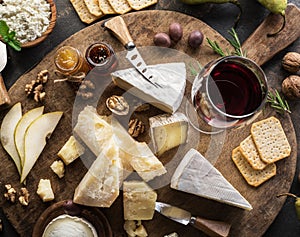 Cheese platter with different cheeses, fruits, nuts and wine on stone background. Top view. Tasty cheese starter