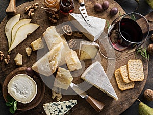 Cheese platter with different cheeses, fruits, nuts and wine on stone background. Top view. Tasty cheese starter