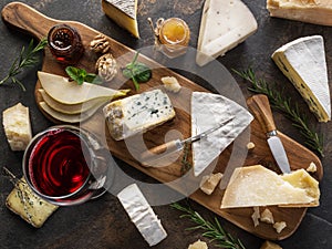 Cheese platter with different cheeses, fruits, nuts and wine on stone background. Top view. Tasty cheese starter