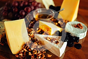 Cheese platter with different cheeses, grapes, nuts, honey, brea