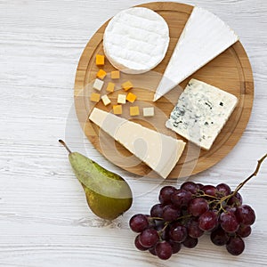 Cheese platter with fruits on a white wooden background. Food for wine, top view. Flat lay, from above. Close-up
