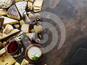 Cheese platter with organic cheeses, fruits, nuts and wine on stone background. Top view. Tasty cheese starter