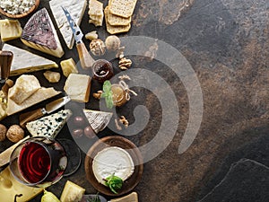 Cheese platter with organic cheeses, fruits, nuts and wine on stone background. Top view. Tasty cheese starter