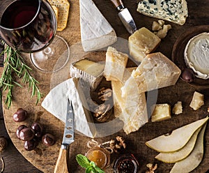 Cheese platter with organic cheeses, fruits, nuts and wine on wooden table. Top view. Tasty cheese starter