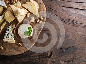Cheese platter with organic cheeses, fruits, nuts on wooden table. Top view