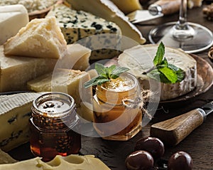 Cheese platter with organic cheeses, fruits, olives and jam on wooden background. Tasty cheese starter