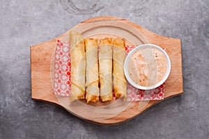 Cheese rolls plate with cocktail sauce served in a wooden plate on a rustic ba