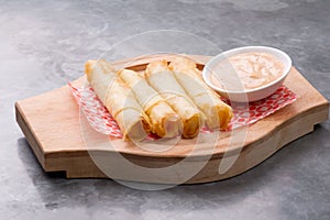 Cheese rolls plate with cocktail sauce served in a wooden plate on a rustic ba