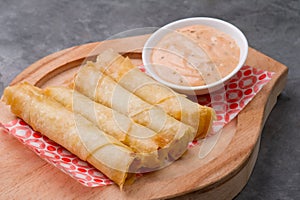 Cheese rolls plate with cocktail sauce served in a wooden plate on a rustic ba