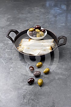 Cheese rolls plate with olives served in a black pan on a rustic background