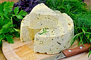 Cheese round homemade with herbs and knife on board