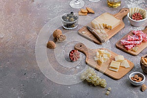 Cheese, salumi, olives, nut and grapes on wooden board, copy space