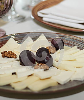 Cheese in plate with nuts and grapes