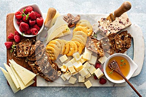 Cheese and snacks board with raspberry and crackers