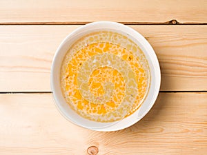 Cheese soup in a white round plate on a wooden background