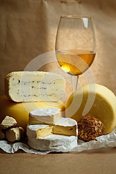 Cheese still life with a glass of wine on a background of parchment paper