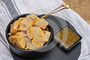 Cheese tasting, small pieces of old Dutch hard cheese and bowl with homemade dill-mustard sauce