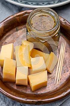 Cheese tasting, small pieces of old Dutch hard cheese and bowl with homemade dill-mustard sauce