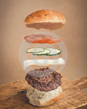tomato and pickle burger with all ingredients in the air