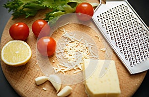 Cheese, tomatoes, garlic with grater on wooden board