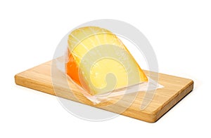 Cheese in vacuum packing on cutting board