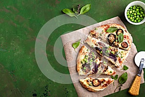 Cheese vegetable tortillas with eggplant, peas, red onion and mozzarella on a green background