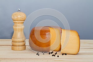 Cheese wheel and slice with wooden peppermill with peppercorns